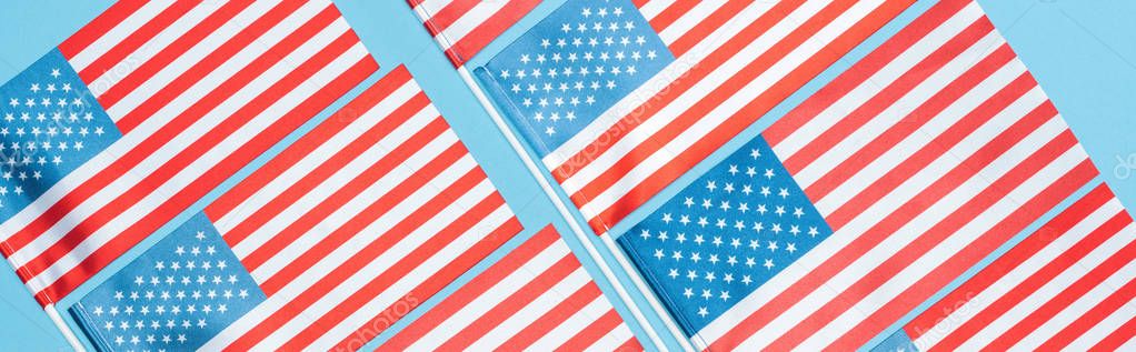 flat lay with american flags on sticks on blue background, panoramic shot 