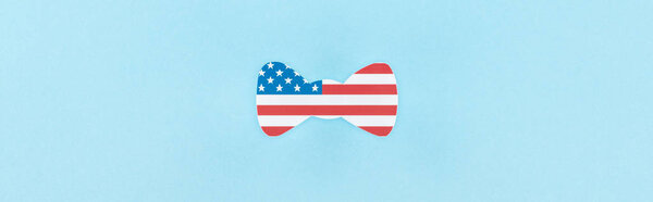 top view of paper cut decorative bow tie made of american flag on blue background, panoramic shot 