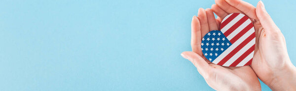 панорамный снимок женщины с сердцем, сделанный из национального американского флага в руках на синем фоне с копировальным пространством
