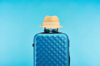 güneş gözlüğü ve saman şapka mavi izole mavi renkli seyahat çantası