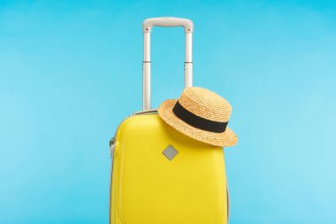 Mavi üzerine saman şapkalı sarı seyahat çantası.