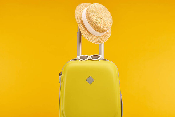 желтая красочная сумка с солнцезащитными очками и соломенной шляпой на ручке
