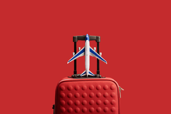 red colorful textured travel bag with plane model isolated on red 