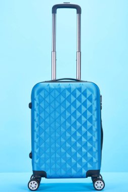 mavi arka plan üzerinde tekerlekler üzerinde kolu ile mavi renkli seyahat çantası