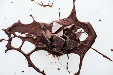 Top view of pieces of dark chocolate with splash of melted chocolate clipart