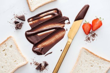 Sıvı çikolata, çikolata, çilek ve tost parçaları ile altın masa bıçağı üst görünümü 