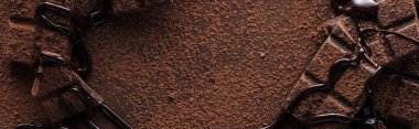 Panoramic shot of pieces of chocolate bar with melted chocolate and cocoa powder clipart
