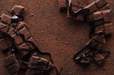 Metal arka planda sıvı çikolata ve kakao tozu ile çikolata parçaları üst görünümü