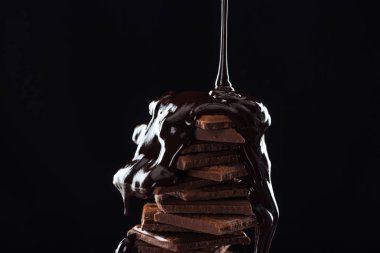 Hot melted chocolate pouring on chocolate stack, isolated on black clipart