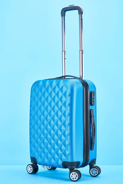 blue colorful suitcase with handle on wheels on blue background