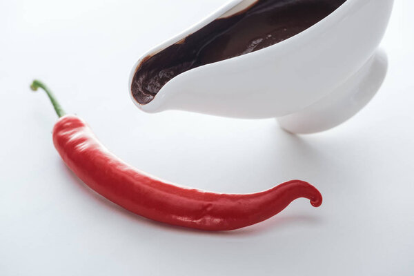 High angle view of chili and sauce boat with melted chocolate on white background 