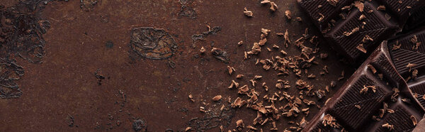 Panoramic shot of pieces of chocolate bar with chocolate chips on metal background 