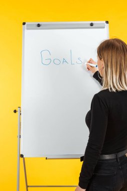 beyaz flipchart yanında duran iş kadını geri görünümü, gol kelime yazma