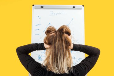 back view of businesswoman standing near white flipchart, holding hand on head clipart