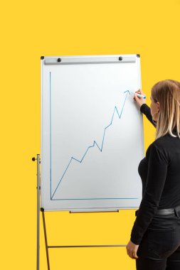 beyaz flipchart yanında duran iş kadını geri görünümü, büyüme grafik çizim, sarı izole ayakta