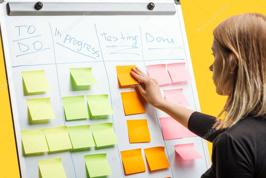 smart businesswoman standing near white flipchart, attaching sticky notes with copy space