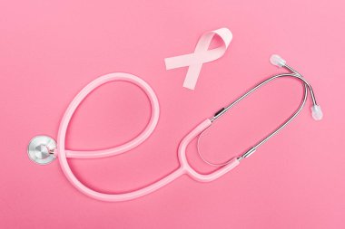 pembe arka plan üzerinde stetoskop ve pembe meme kanseri işareti üst görünümü