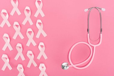 pembe arka plan üzerinde stetoskop ve pembe meme kanseri işaretleri üst görünümü