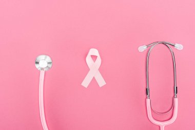 pembe arka plan üzerinde stetoskop ve pembe meme kanseri sembolü üst görünümü