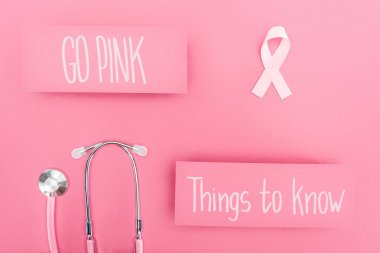 top view of stethoscope and pink breast cancer sign near go pink and things to know lettering on pink background clipart