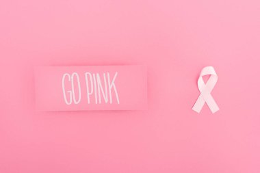 top view of go pink lettering on card and breast cancer sign on pink background clipart