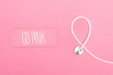 stetoskop üst görünümü ve pembe arka plan üzerinde pembe yazı gitmek