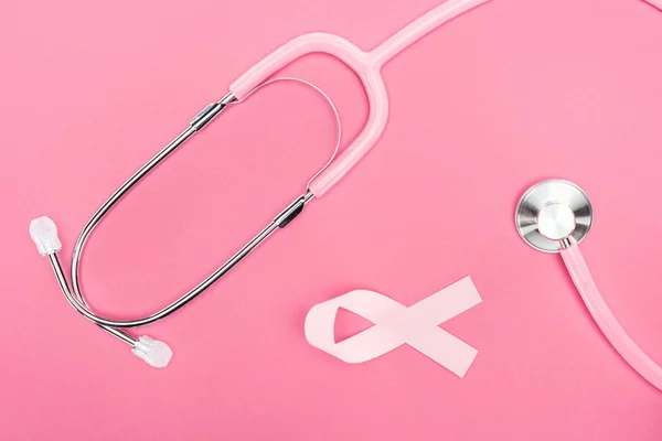 听诊器和粉红色乳腺癌丝带在粉红色背景的顶视图 — 图库照片
