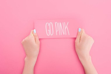 partial view of woman holding pink card with go pink lettering on pink background clipart