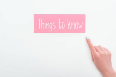 partial view of woman pointing with finger at pink card with things to know lettering on white background clipart