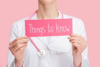 beyaz ceket ve stetoskop tutan doktor kırpılmış görünümü şeyler pembe izole yazı bilmek