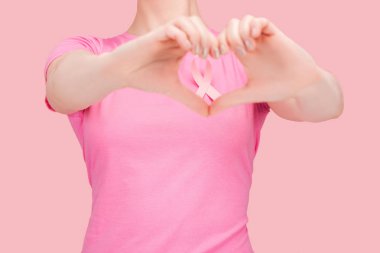 pembe izole meme kanseri kurdele etrafında elleri ile kalp işareti gösteren pembe t-shirt kadın kırpılmış görünümü