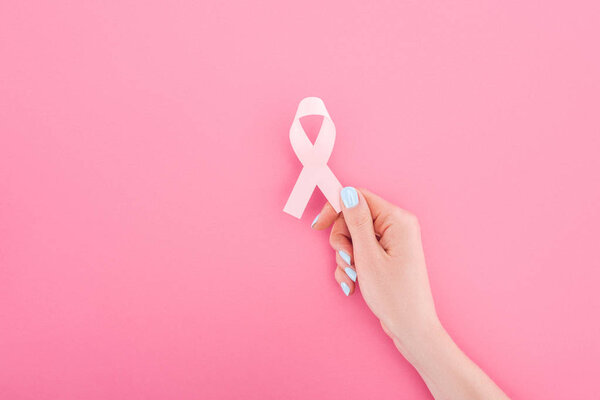 partial view of woman with pink breast cancer sign on pink background