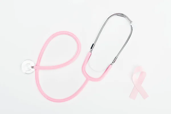 听诊器和粉红色乳腺癌弓在白色背景的顶视图 — 图库照片