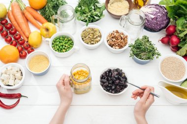 ahşap beyaz masa üzerinde salata ile kavanozda fasulye ekleyerek kadın kırpılmış görünümü 