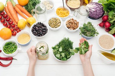 ahşap beyaz masa üzerinde salata ile kavanoza otlar ekleyerek kadın kırpılmış görünümü 