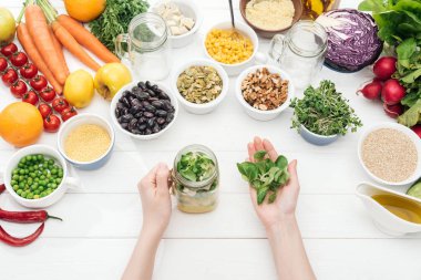 ahşap beyaz masa üzerinde salata ile cam kavanoza otlar ekleyerek kadın kırpılmış görünümü 