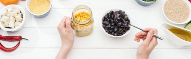 ahşap beyaz masa, panoramik çekim salata ile kavanozda fasulye ekleyerek kadın kırpılmış görünümü