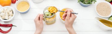 ahşap beyaz masa, panoramik çekim salata ile kavanoza mısır ekleyerek kadın kırpılmış görünümü