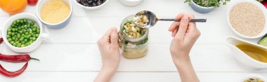 ahşap beyaz masa, panoramik çekim salata ile kavanozda kabak çekirdeği ekleyerek kadın kısmi görünümü
