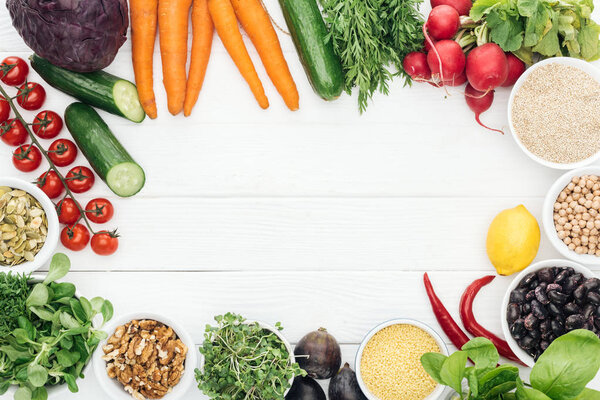 top view of fresh fruits and vegetables near glass jars on wooden white table with copy space