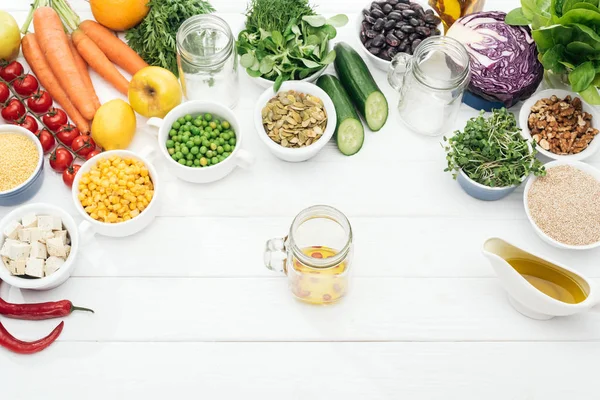 在木制白色餐桌上的玻璃罐附近 在水果和蔬菜附近 玻璃罐与油和辣椒的顶视图 — 图库照片