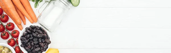 コピースペース パノラマショットと木製の白いテーブルのガラス瓶の近くにおいしい野菜のトップビュー — ストック写真