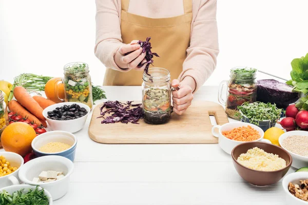 Cropped view of woman in apron adding sliced red cabbage in glass jar on wooden table isolated on white — Stock Image Cropped View Woman Apron Adding Sliced Red Cabbage Glass Jar Stock Photo