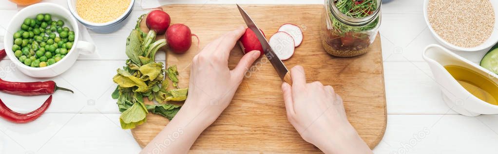 cropped view of woman cutting radish on wooden chopping board, panoramic shot