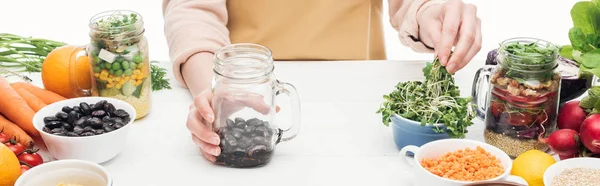 Cropped View Woman Apron Adding Greens Glass Jar Beans Wooden — Stock Photo, Image