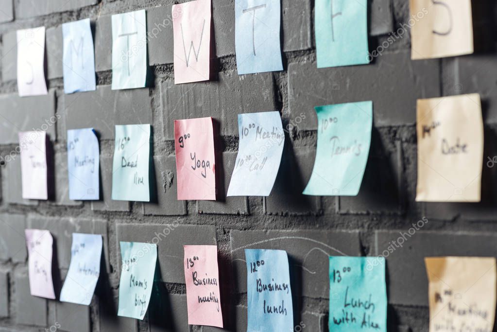 selective focus of colorful colorful sticker notes on black brick wall