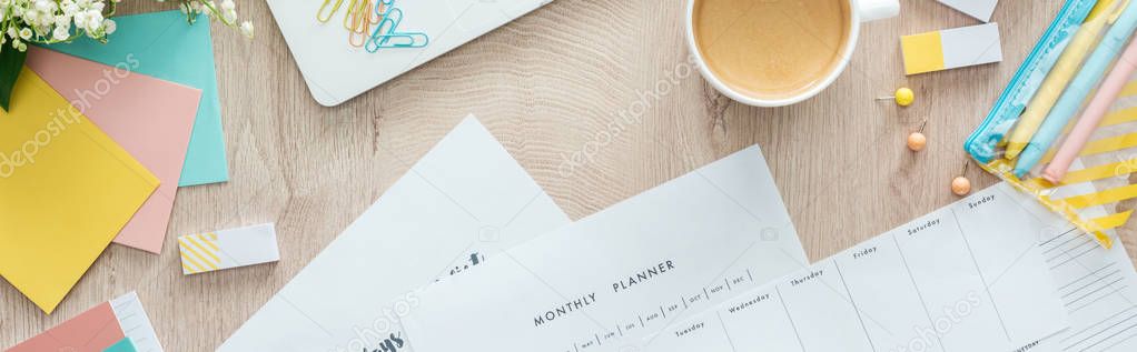 panoramic view of coffee in white cup, planners and flowers with stationery on wooden table