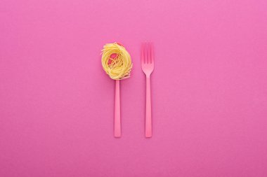 pembe arka plan üzerinde pembe kaşık pembe plastik çatal ve makarna