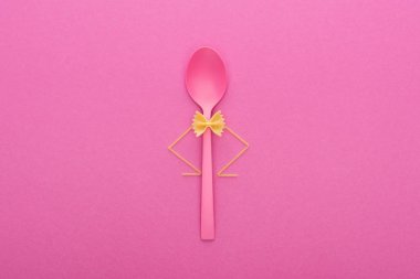 plastik kaşık ve spagetti pembe izole üzerinde pişmemiş farfalle makarna