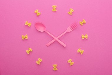 pembe üzerine izole çapraz pembe plastik çatal ve kaşık ile saat kavramı